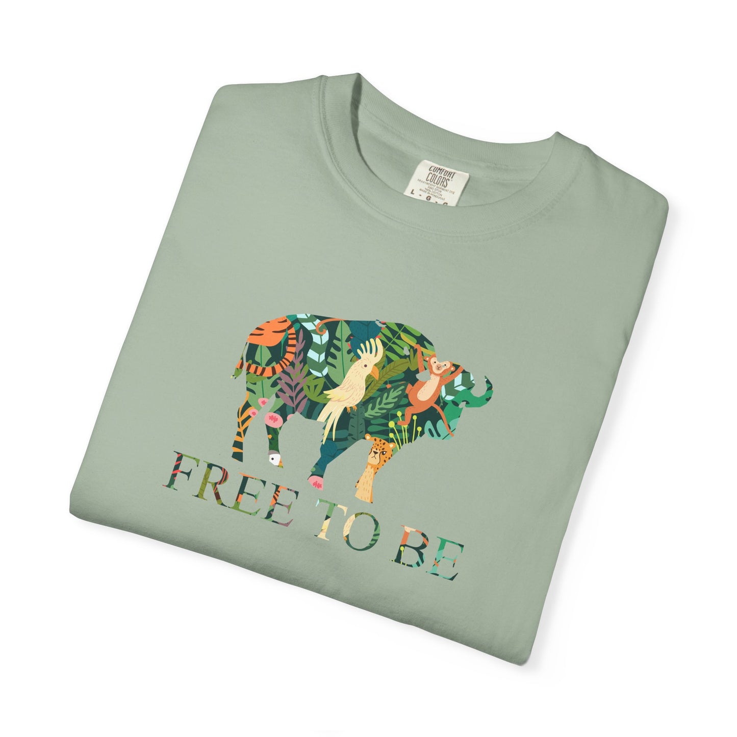 Folded green t-shirt with a colorful animal design and 'FREE TO BE' text on a white background
