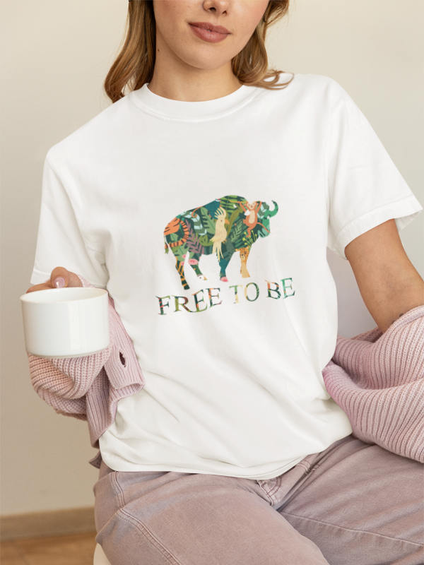 Person wearing a white t-shirt with a colorful buffalo graphic and 'FREE TO BE' text.