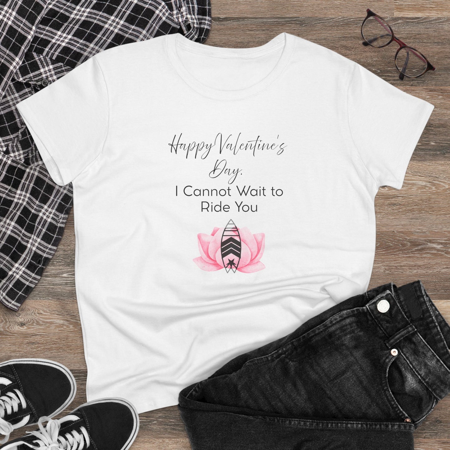 White t-shirt with Valentine's Day design on a wooden surface with casual clothing items.
