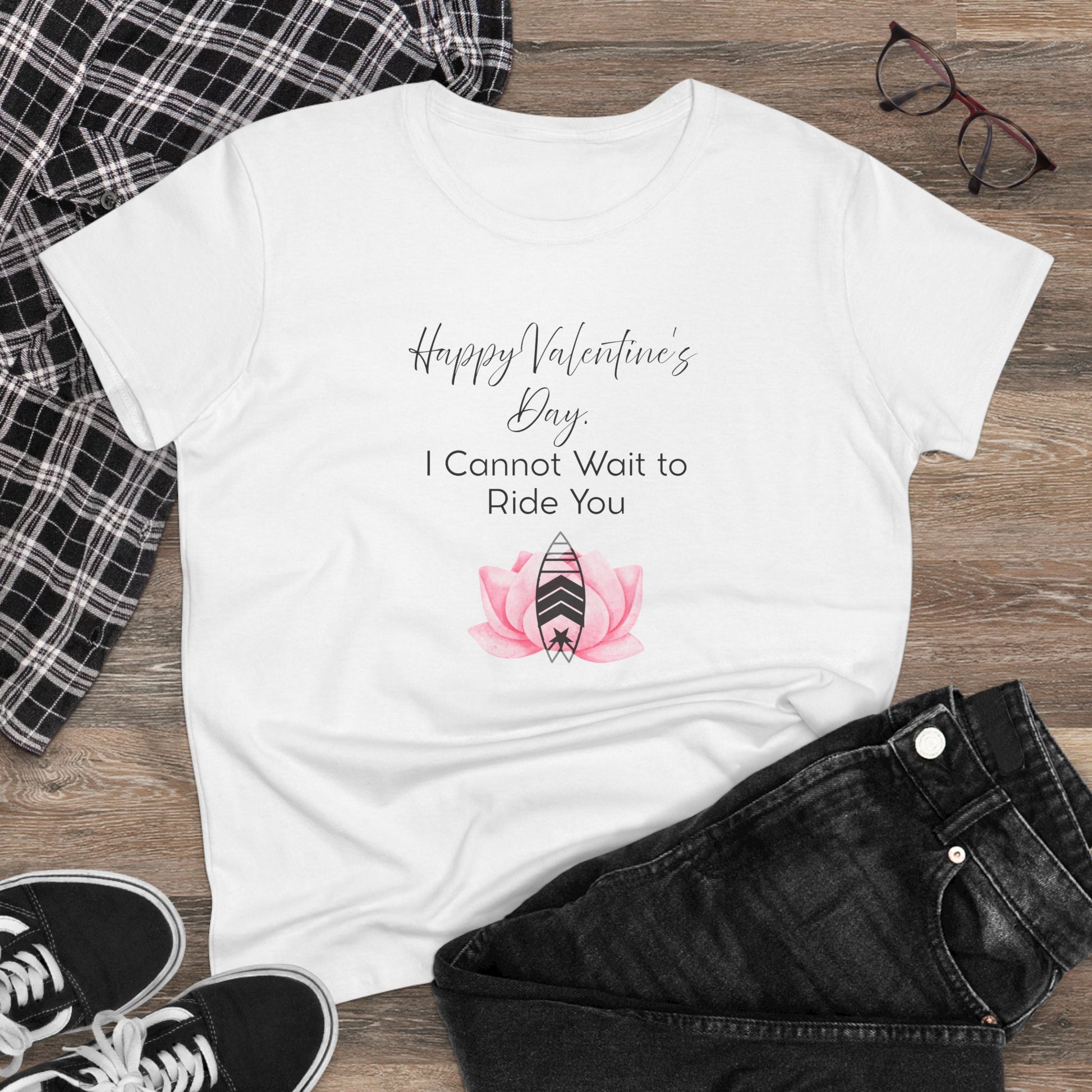 White t-shirt with Valentine's Day design on a wooden surface with casual clothing items.