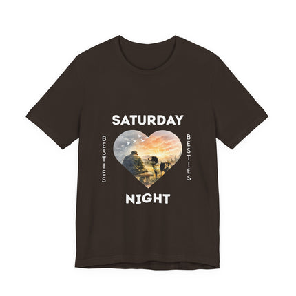 A dark brown short-sleeve t-shirt with a graphic on the front that reads 'SATURDAY NIGHT Besties' in white text, surrounding a heart-shaped scenic photo print of a vet who is sitting alone on a bench. His loving dog is gazing at him. 