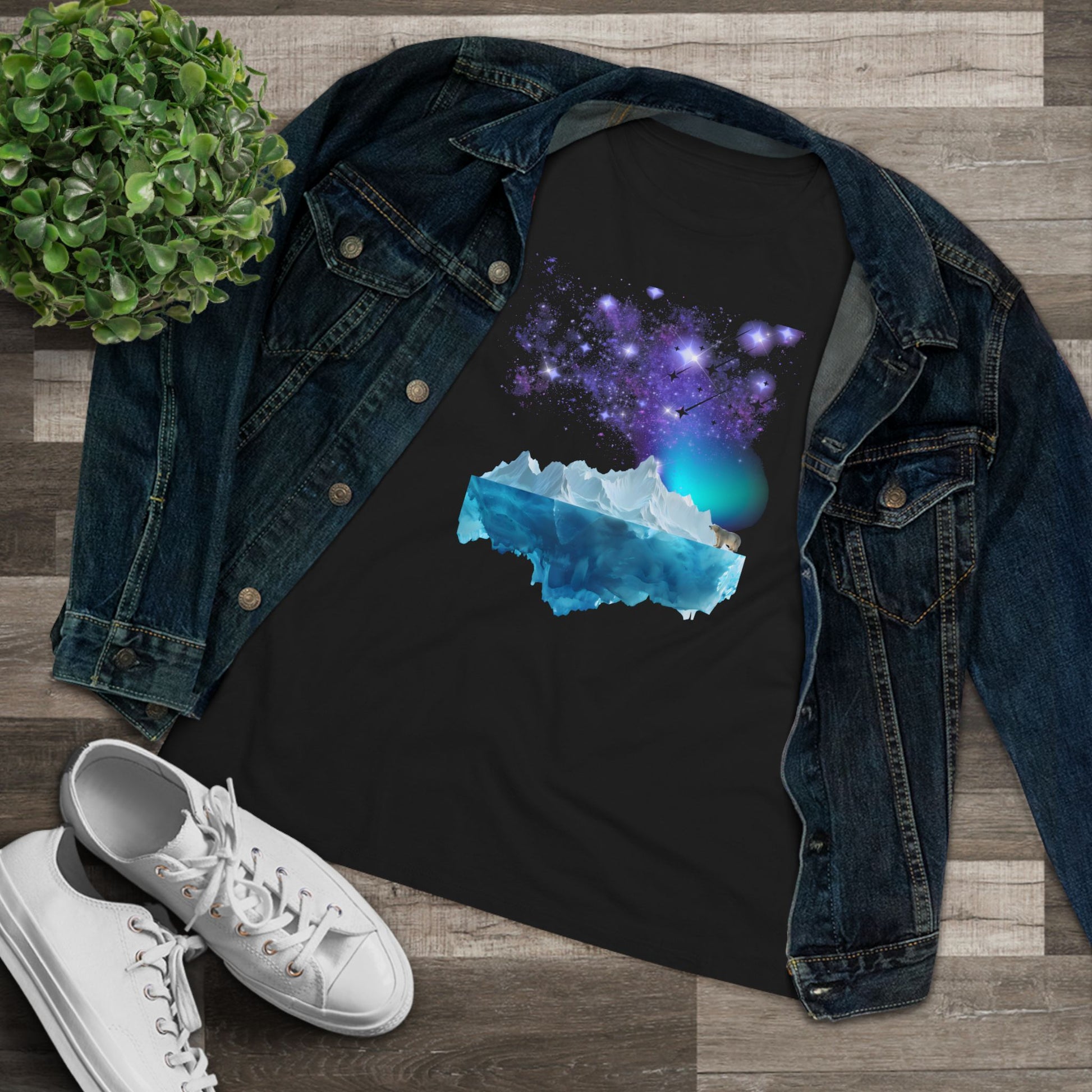 Black t-shirt with a galaxy design, denim jacket, and white sneakers on a wooden surface.