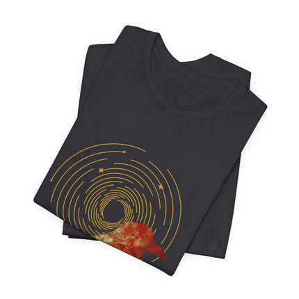 Raven dreamcatcher boho graphic with golden celestial rings and teal textured artwork on a folded black t-shirt.