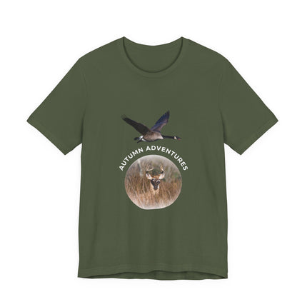 An olive green short-sleeve t-shirt with a central graphic print featuring a flying goose, a deer head inside a circular frame, and the text 'AUTUMN ADVENTURES' arched above the circle.