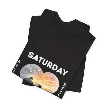 A black folded t-shirt with the lettering SATURDAY, underneath the heart shape with birds and a sunset.