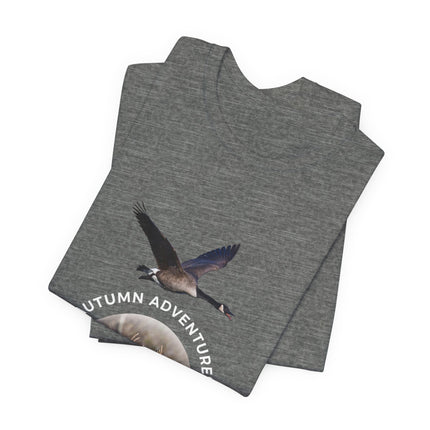 A folded heather gray t-shirt featuring a graphic of a flying Canada goose with the text 'AUTUMN ADVENTURE' printed in white along the bottom curve of the graphic, set against a plain white background.