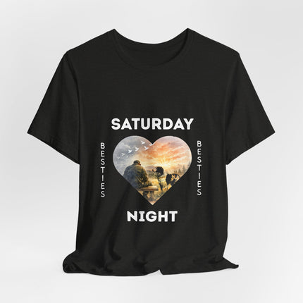 A black short-sleeve t-shirt with a graphic print on the front. The design features the text 'SATURDAY' and 'NIGHT' in white capital letters framing a heart-shaped illustration of veteran on a bench with his loving dog staring at him with love.