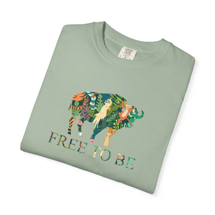 Folded green t-shirt with a colorful animal design and 'FREE TO BE' text on a white background