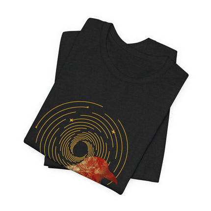 Raven dreamcatcher boho graphic with golden celestial rings and teal textured artwork on a folded black t-shirt.