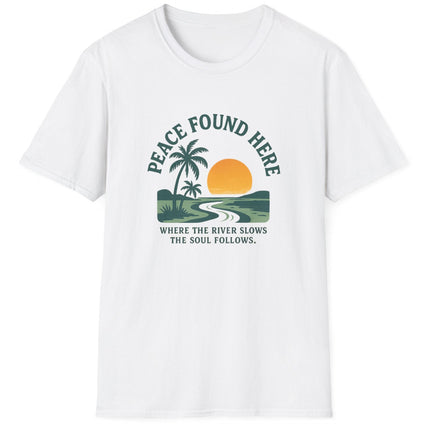 White t-shirt with a graphic design featuring a palm tree, sun, and river, with text 'Peace Found Here'.