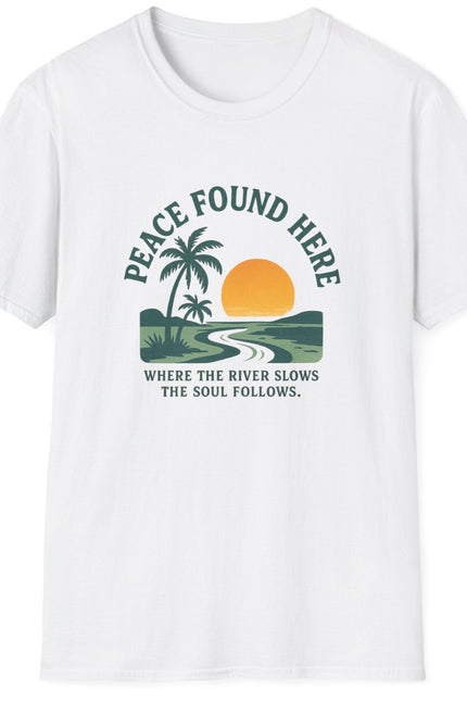 White t-shirt with a graphic design featuring a palm tree, sun, and river, with text 'Peace Found Here'.