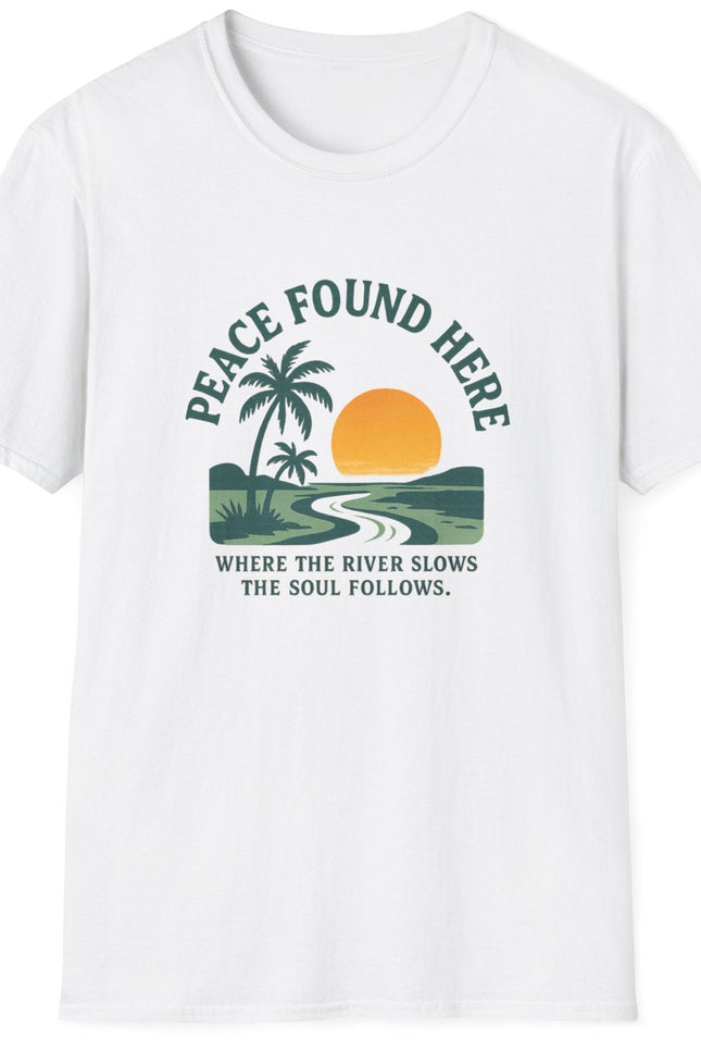 White t-shirt with a graphic design featuring a palm tree, sun, and river, with text 'Peace Found Here'.