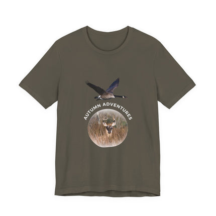 An olive green short-sleeve t-shirt with a graphic on the front showing a flying goose and a deer head inside a circular frame with the text 'AUTUMN ADVENTURES'.