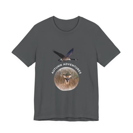 A dark gray short-sleeve t-shirt with a graphic on the front showing a flying goose above a circular deer head in a field, with the text 'AUTUMN ADVENTURES' arched above the circle.
