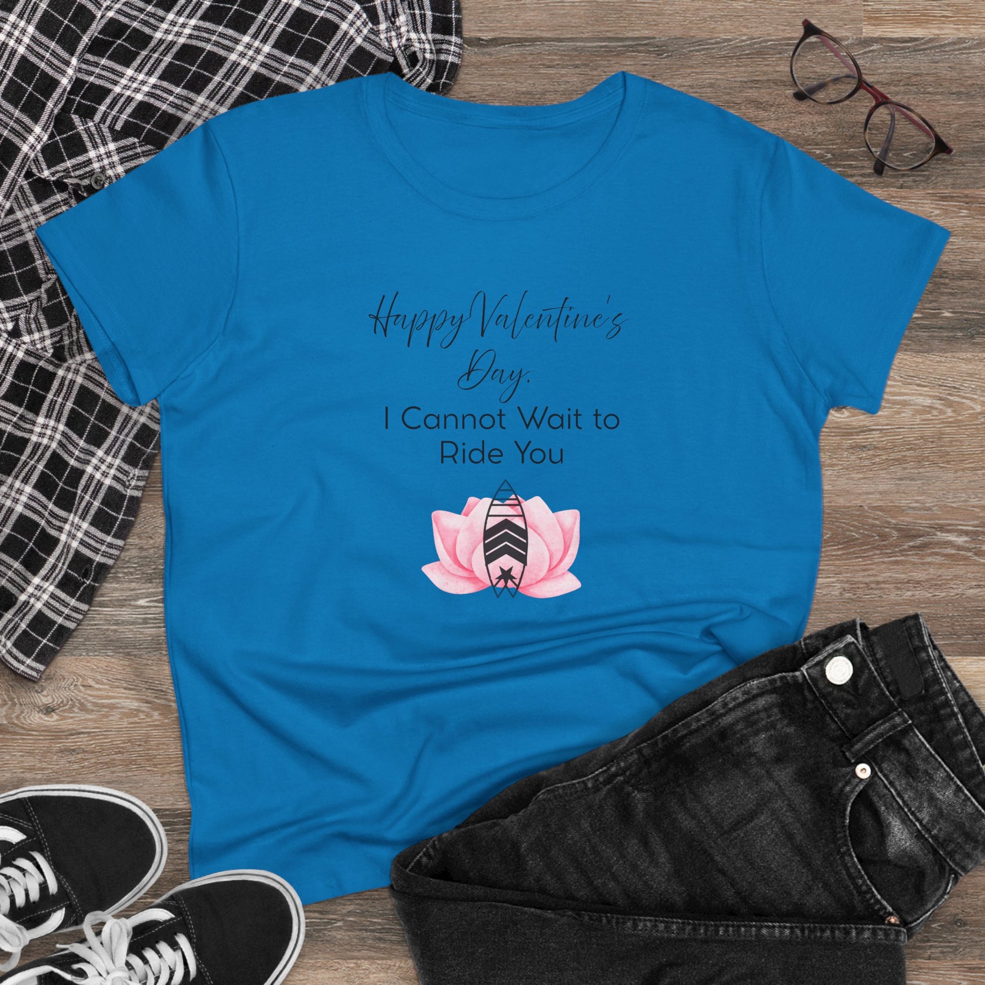 Blue t-shirt with Valentine's Day design on a wooden surface with casual items.