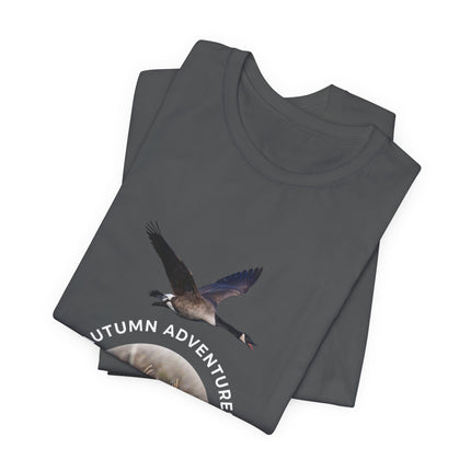 A dark gray folded t-shirt featuring a graphic of a flying Canada goose and the text 'AUTUMN ADVENTURE' on a white background.