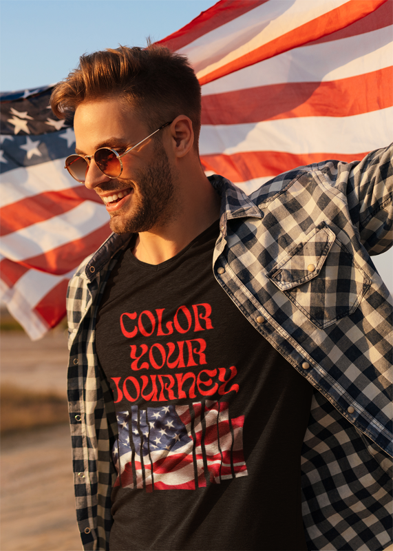 Man wearing a black t-shirt with 'Color Your Journey' text and an American flag design, standing in front of an American flag.