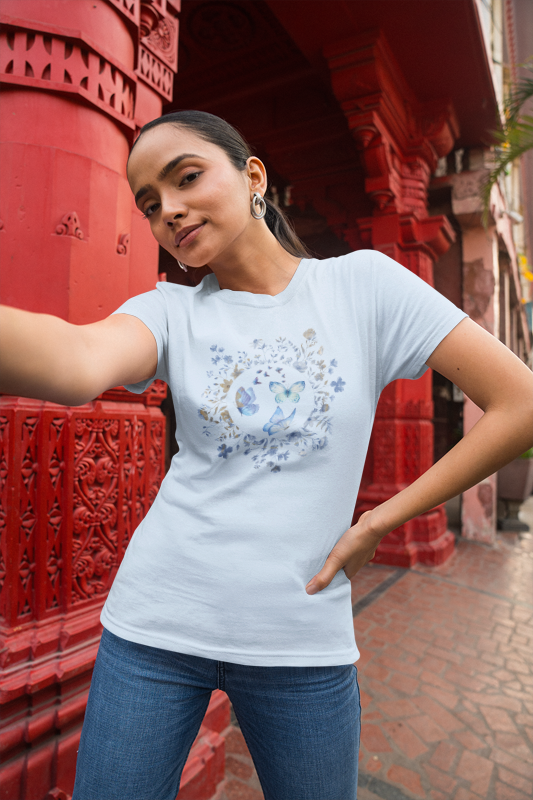 Woman wearing a light blue t-shirt with a floral design in front of red architectural elements.
