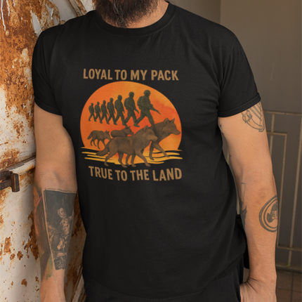 Man wearing a black t-shirt with a graphic design and text, standing against a wall.
