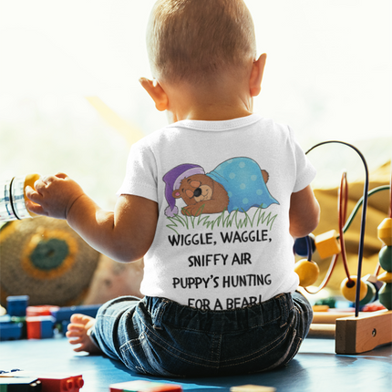 Child wearing a shirt with a cartoon design and text, surrounded by toys on a light background
