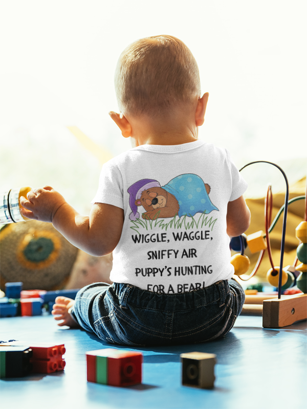 Child wearing a shirt with a cartoon design and text, surrounded by toys on a light background