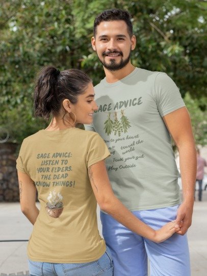 A man and a woman wearing matching sage green and tan graphic t-shirts with 'Sage Advice' text and illustrations, standing outdoors in a park-like setting.