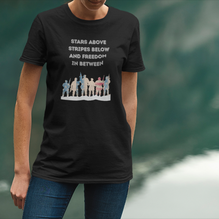 Person wearing a black t-shirt with a graphic and text, standing against a blurred green background.