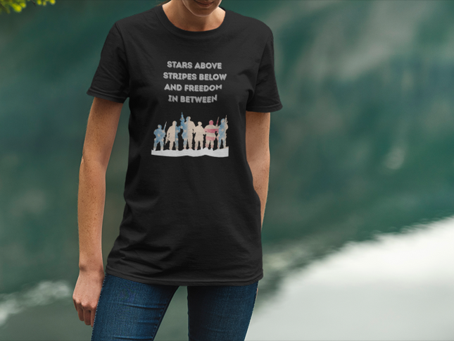 Person wearing a black t-shirt with a graphic and text, standing against a blurred green background.