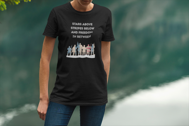 Person wearing a black t-shirt with a graphic and text, standing against a blurred green background.