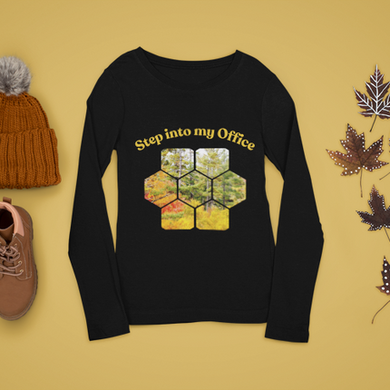 Black sweater with honeycomb design and text, brown beanie, brown shoes, and autumn leaves on a yellow background