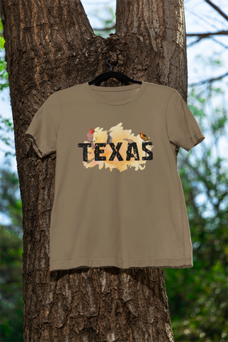 Green t-shirt with 'TEXAS' printed on it hanging on a tree