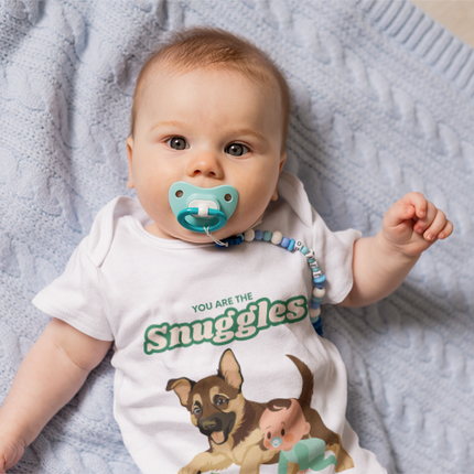 Baby wearing a onesie with a dog illustration and text, lying on a soft surface.